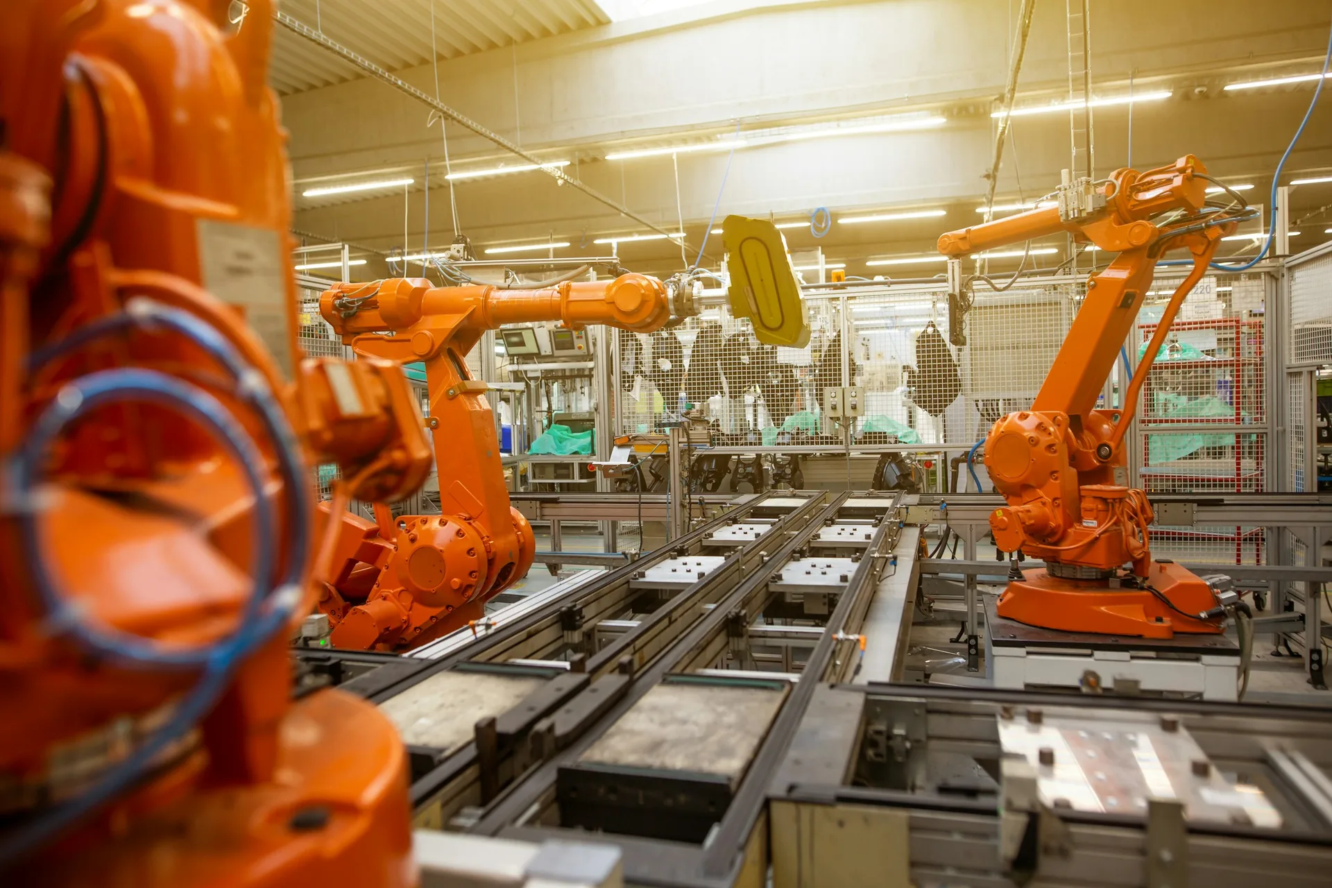 Orange industrial robotic arms arranged along an automated factory production line.